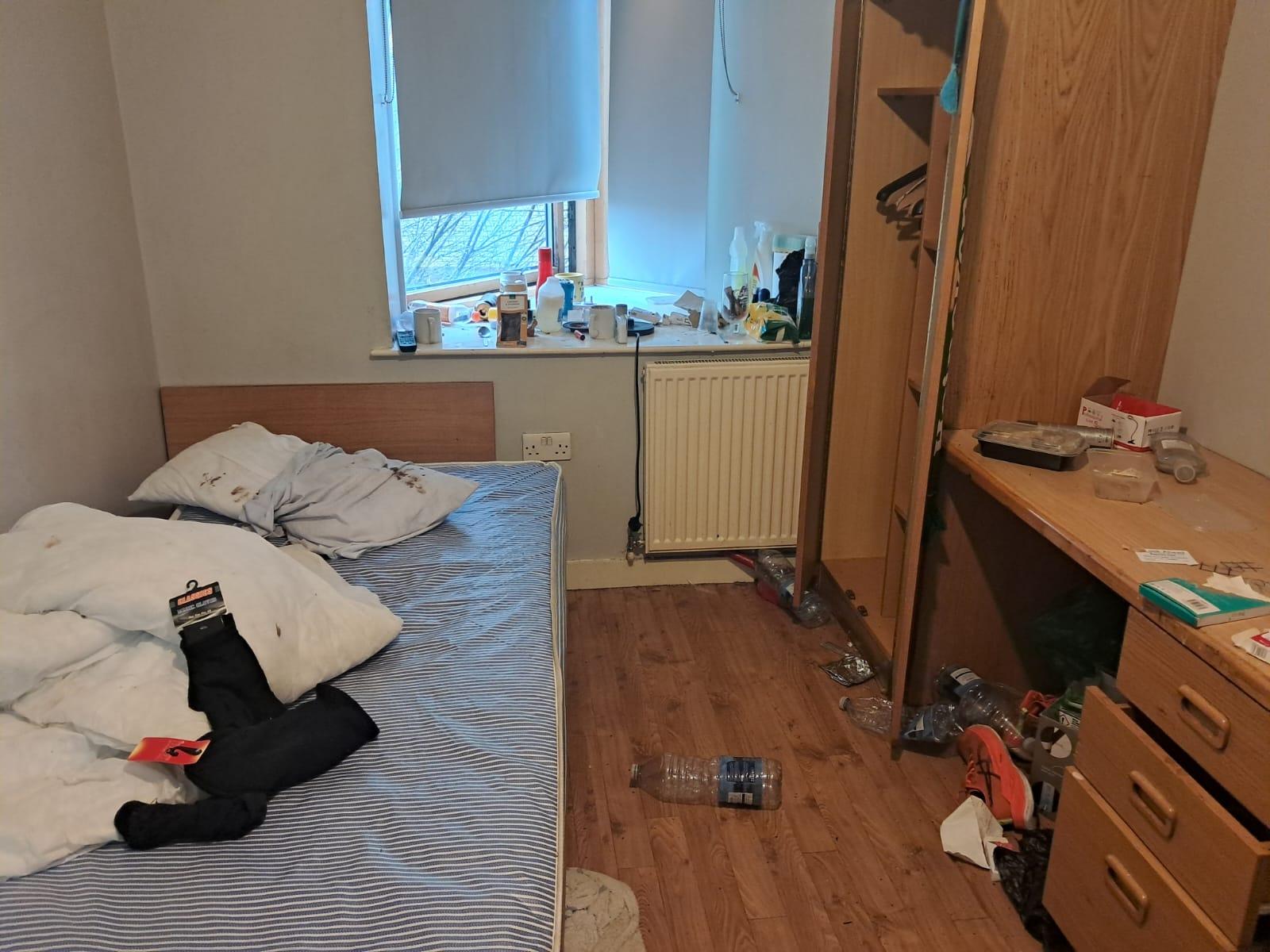 Wardrobe and desk area cluttered with rubbish before a deep clean
